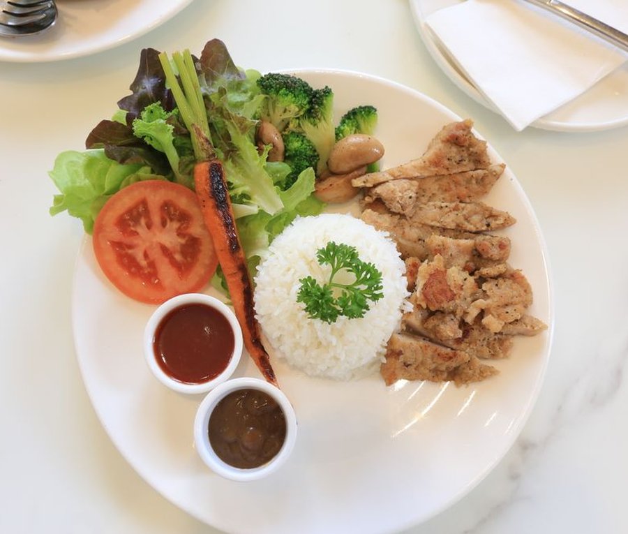 Grilled chicken with rice, salad, and broccoli on a white plate